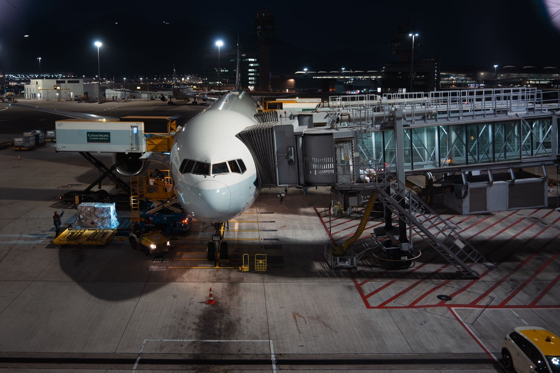 A wide-body aircraft being loaded at an airport stand at night